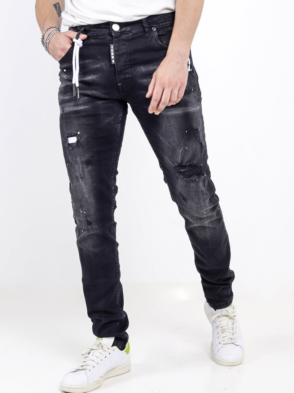 A man wearing black jeans and a white MODERO t - shirt.