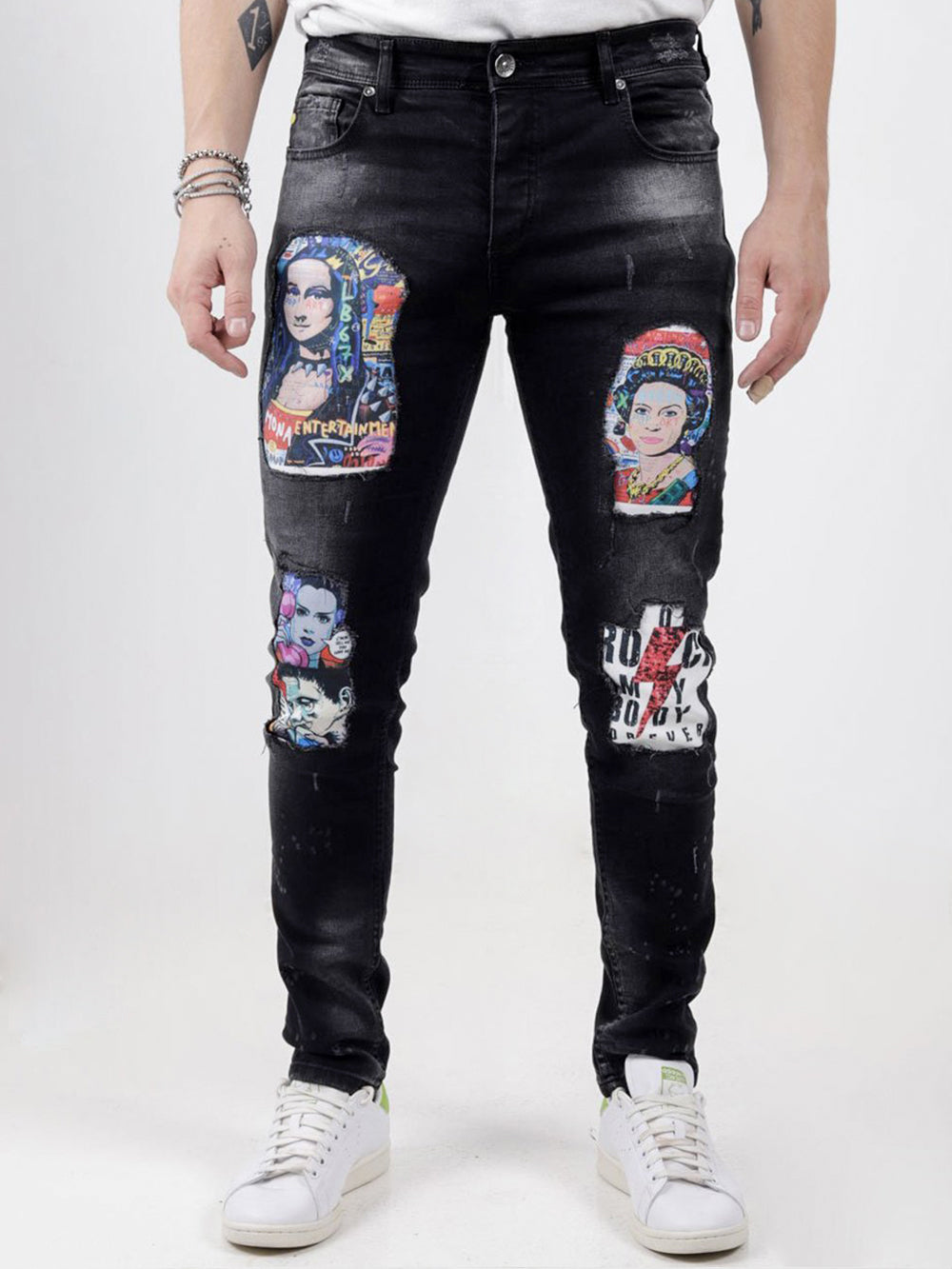 A man wearing a pair of MOONLISA black denim jeans with embroidered patches.