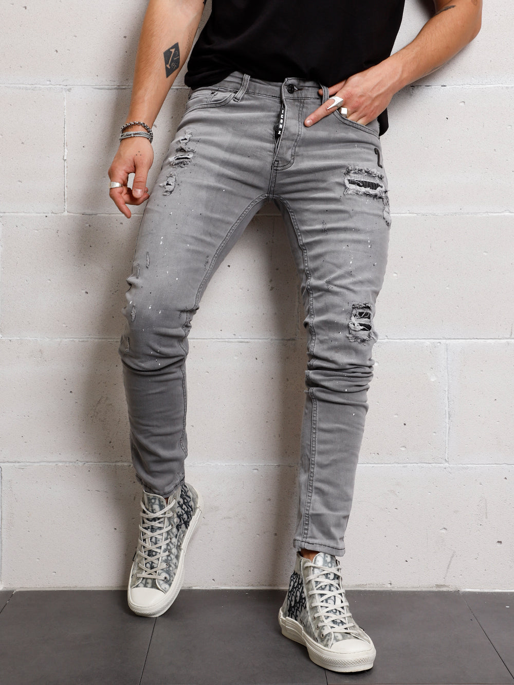 A man in grey jeans leaning against a SMOKE SPLASH.