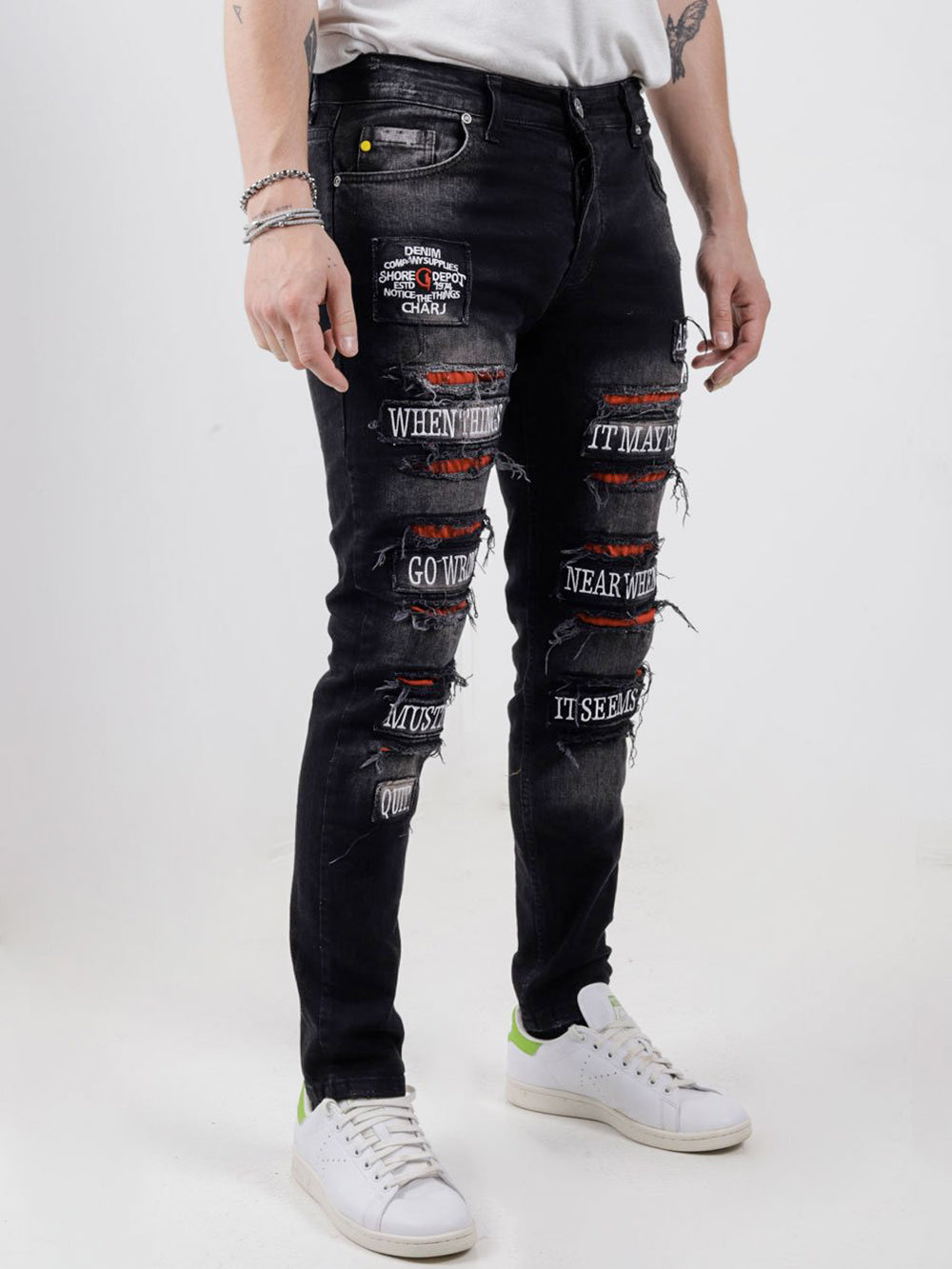 A man wearing PAW TRAIL ripped jeans and a t - shirt.