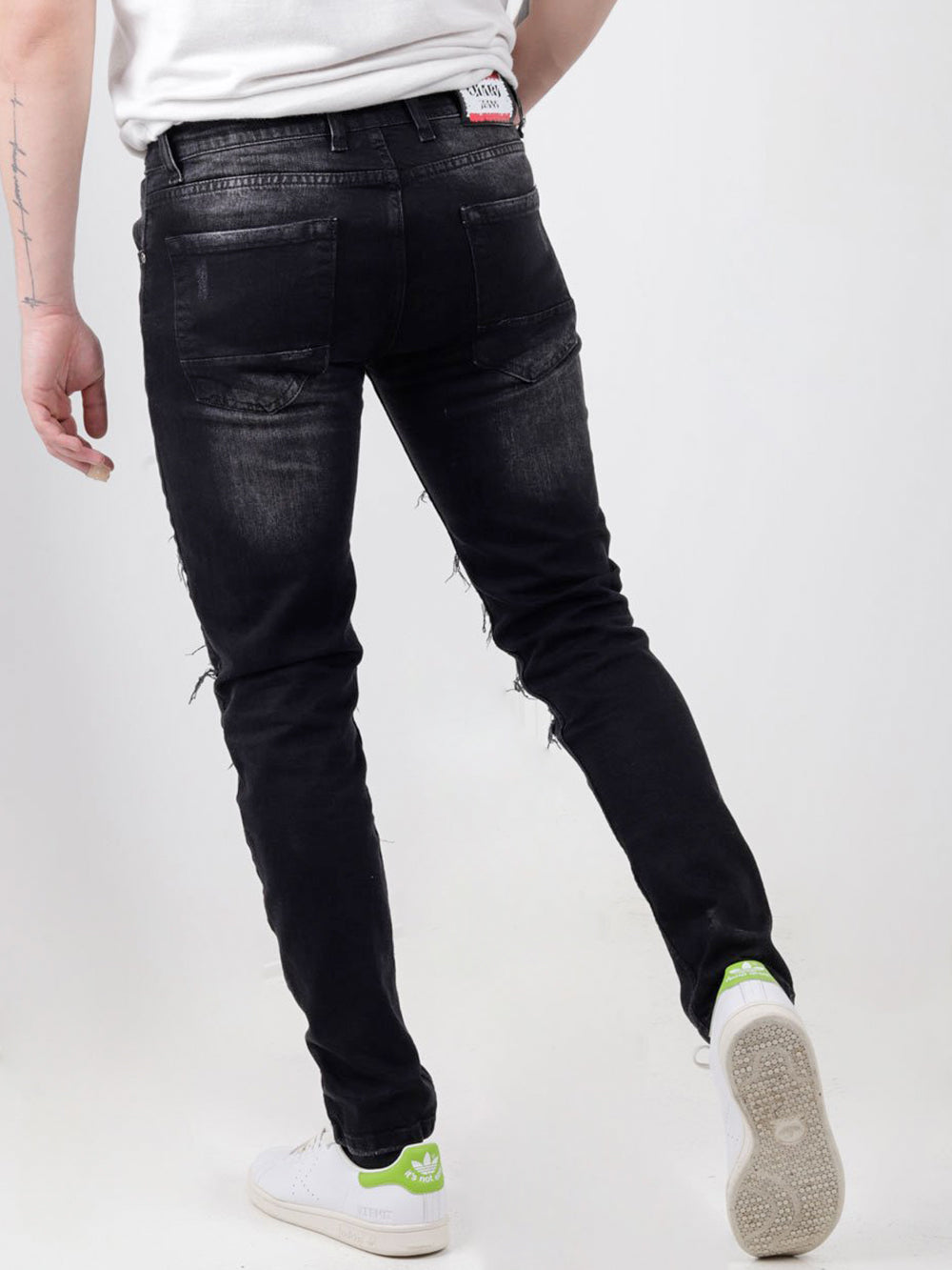 A man wearing black PAW TRAIL jeans and a white PAW TRAIL t-shirt.