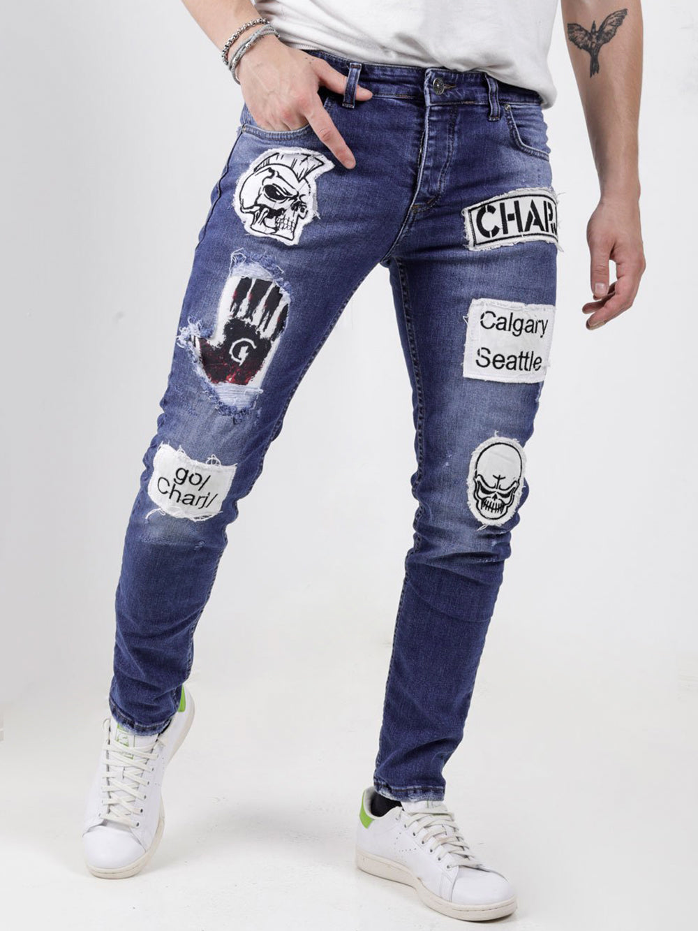 A man wearing a pair of HEADSTONE jeans with patches on them.
