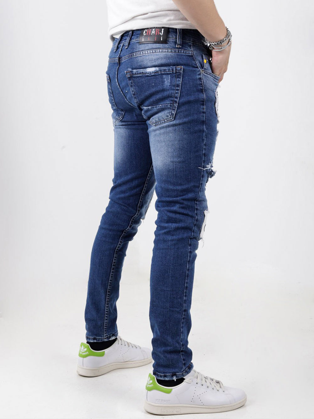 The back of a man wearing blue jeans and white sneakers HEADSTONE.