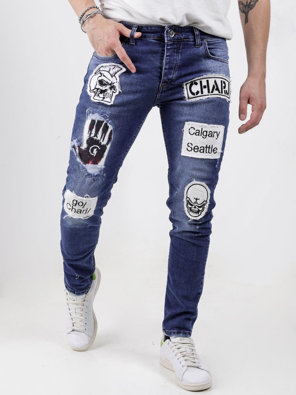 A man wearing a pair of HEADSTONE jeans with patches on them.