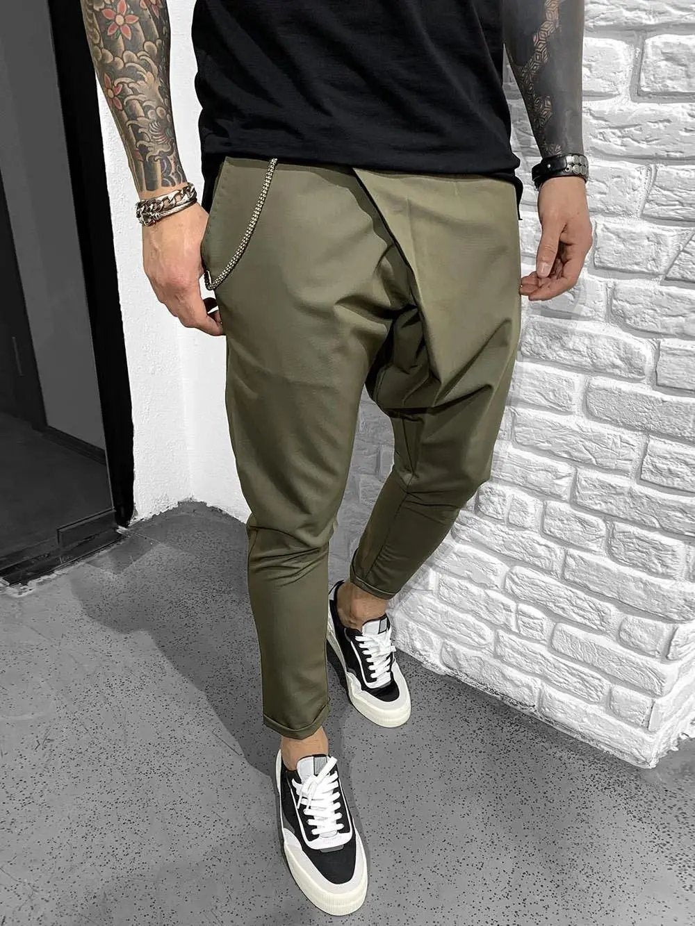 A man with tattoos wearing khaki pants made of elastic fabric for a comfortable and smooth feel.