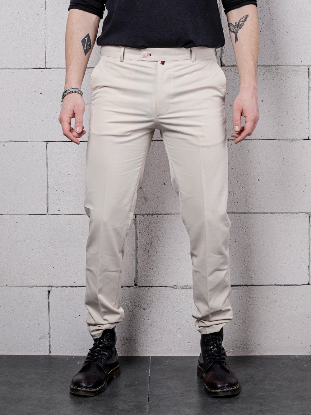 A man wearing VANILLA PANTS standing against a brick wall.