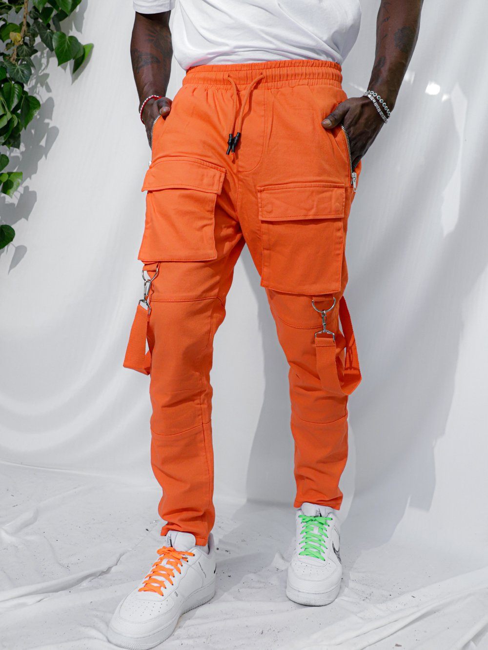 A man wearing ORANGE BRONX cargo pants and green sneakers.