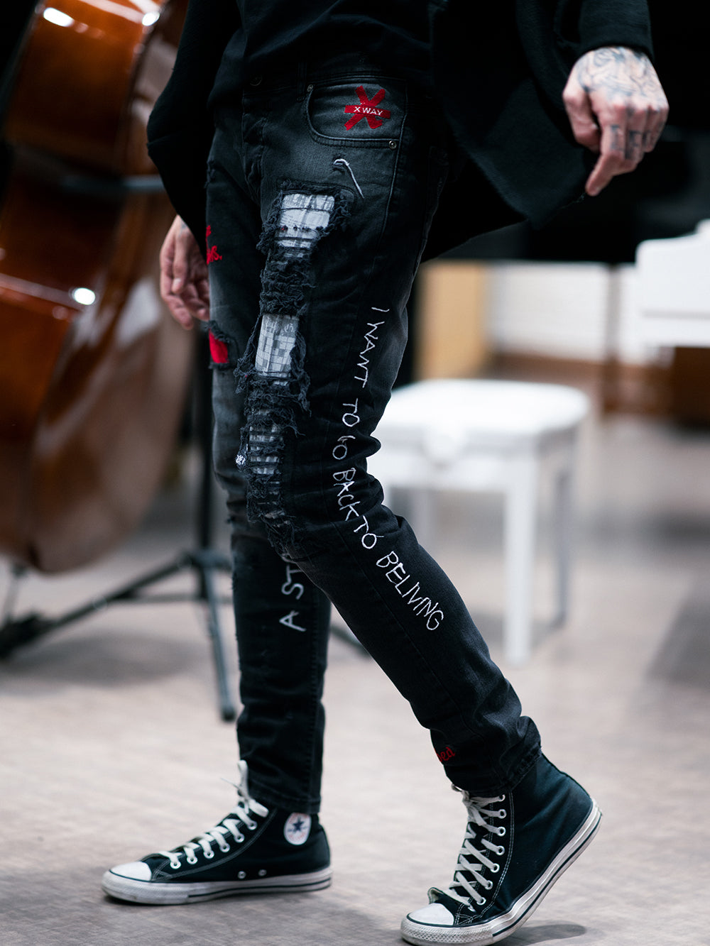 A man wearing a pair of black jeans and a pair of SKYSCRAPER sneakers.