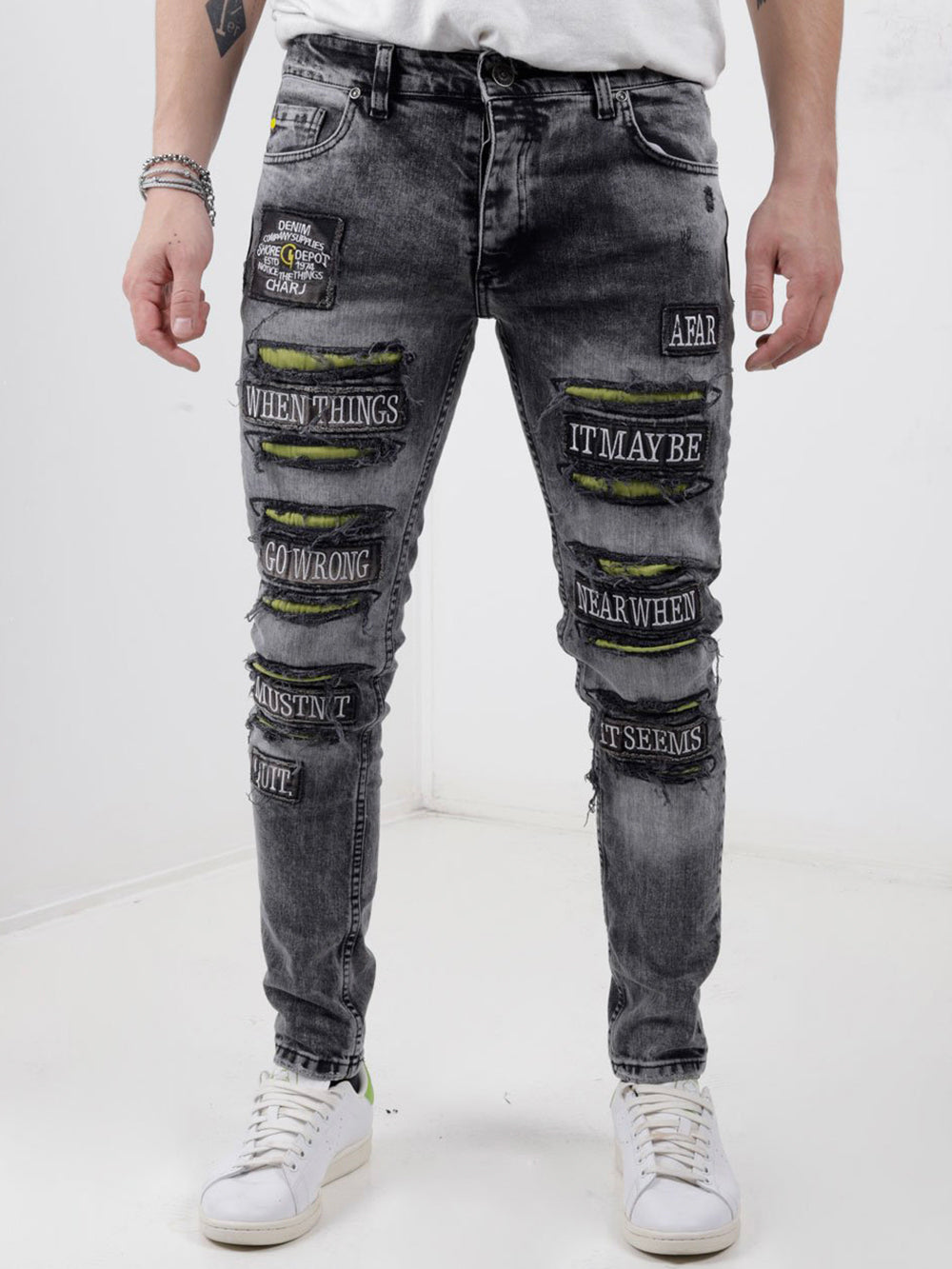 A man wearing a pair of IMPROPER with patches on them.