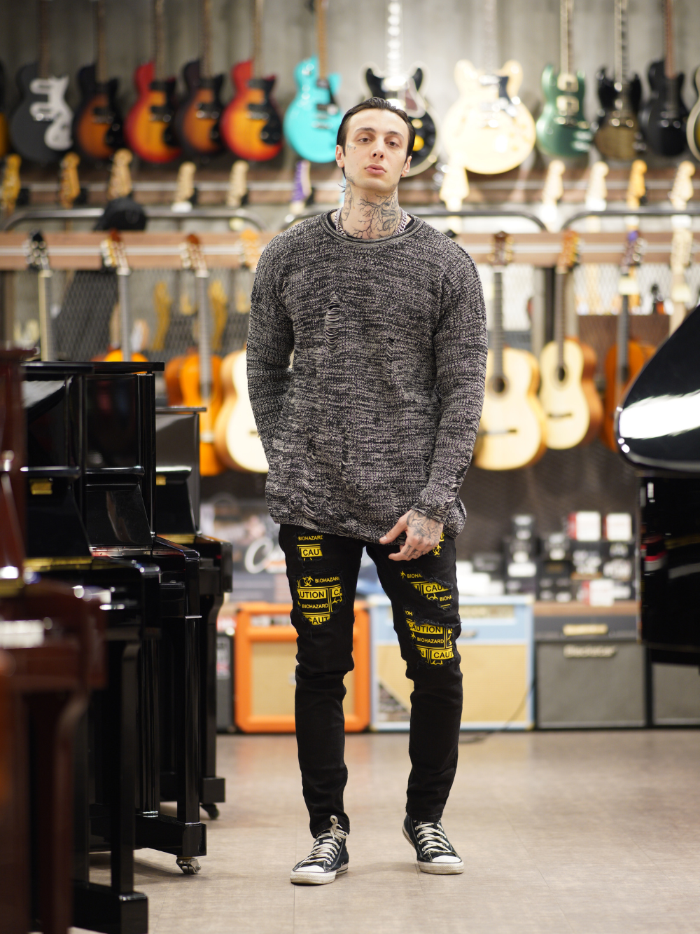 A man standing in a music store admiring the soft feel of the DISTRESSED GENTLEMAN SWEATER | GRAY.