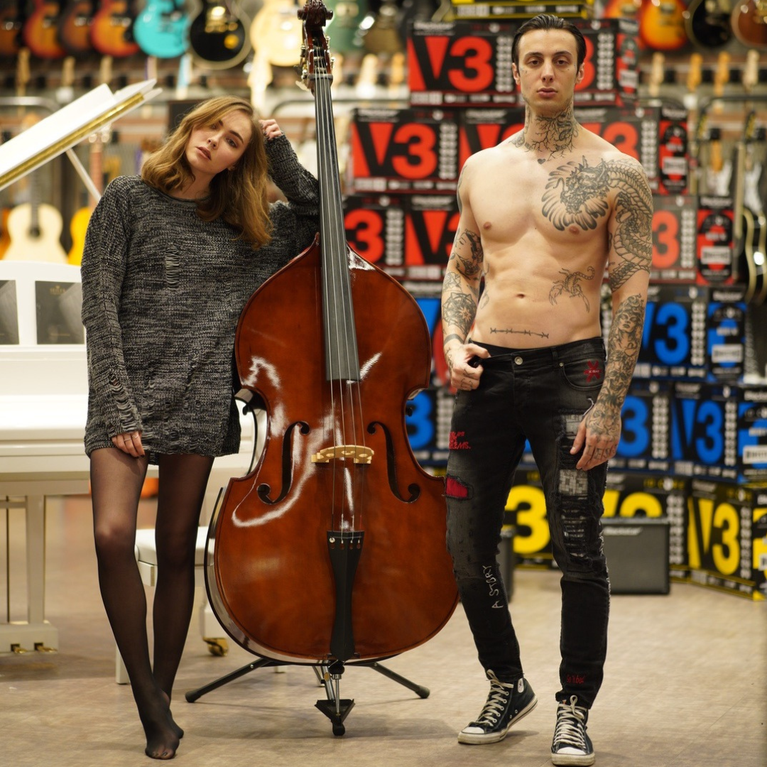 Male and Female model wearing SERNES brand streetwear clothing posing next to a upright bass