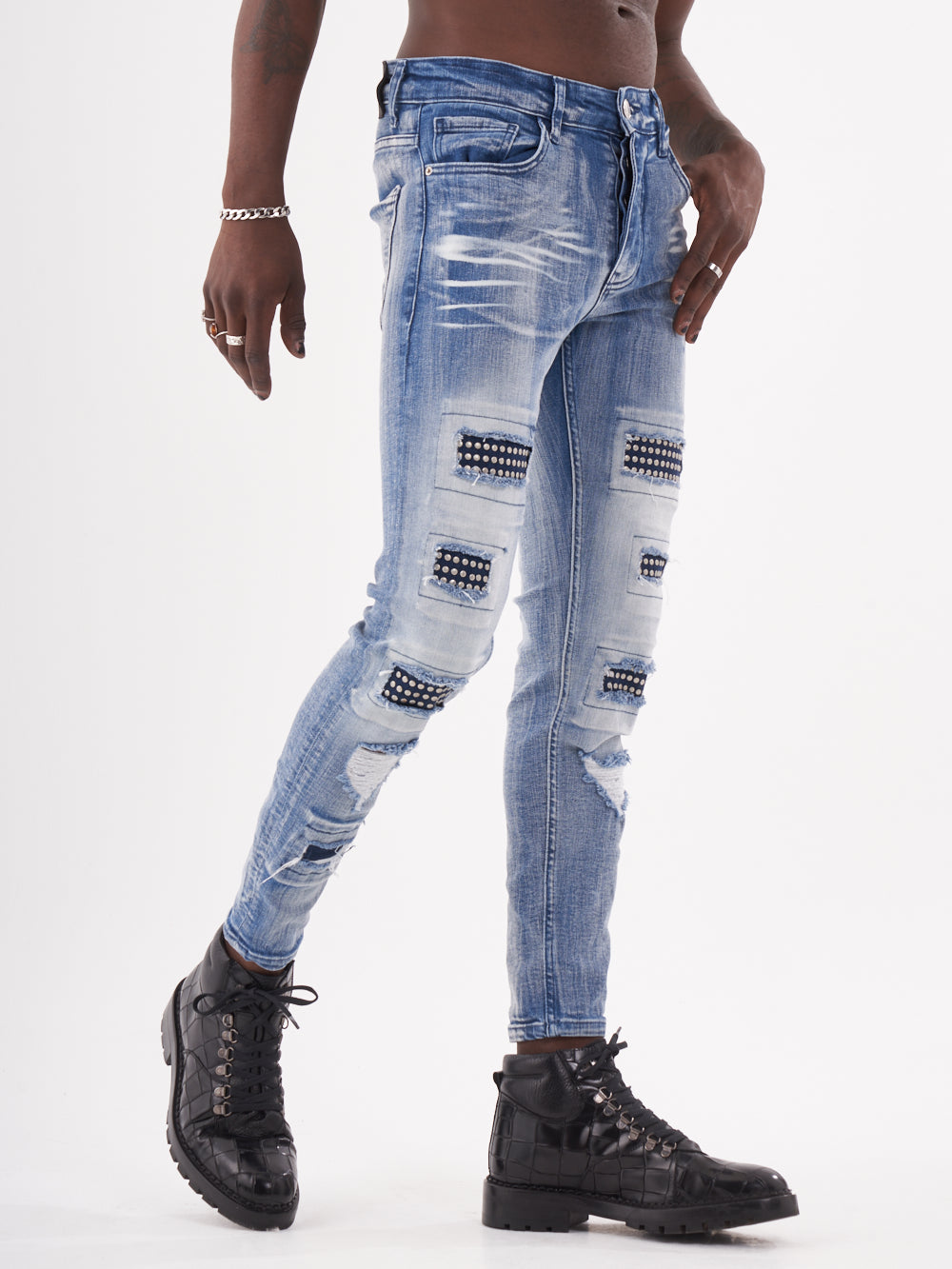 A man wearing MUTANT ripped jeans and a t - shirt.