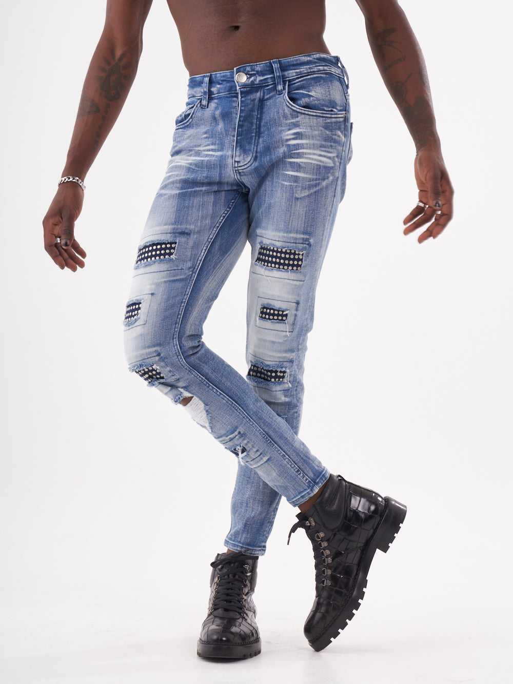 A man in ripped jeans standing on a white background, wearing the MUTANT.