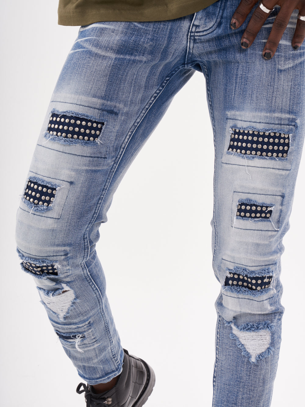 A man wearing a pair of MUTANT jeans with studded patches.
