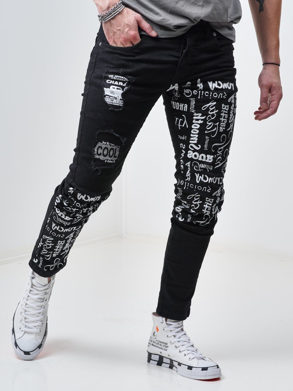 Side shot of a man wearing the skinny fit streetwear jeans called THE MECHANIC by SERNES with lots of text printed on it