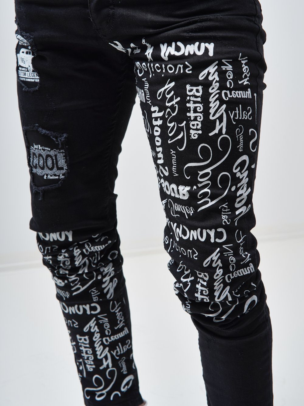 Close up shot of the printed text on the skinny fit streetwear jeans called THE MECHANIC by SERNES with lots of text printed on it