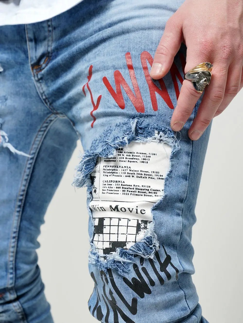 A man is holding a pair of BANKSY jeans that have been torn apart.