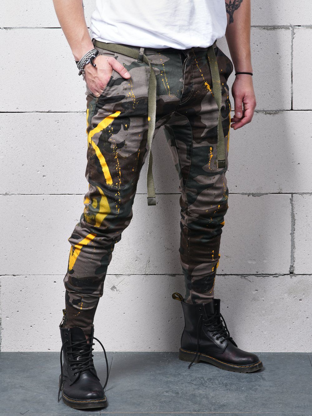 A man wearing KONGOS skinny fit camouflage cargo pants with yellow stripes.