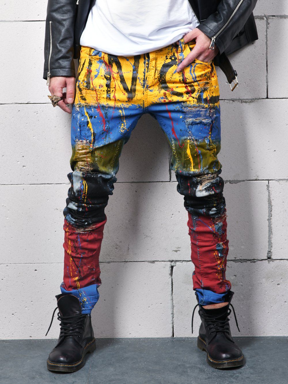 A man wearing a pair of jeans with TOO MUCH splatters on them.