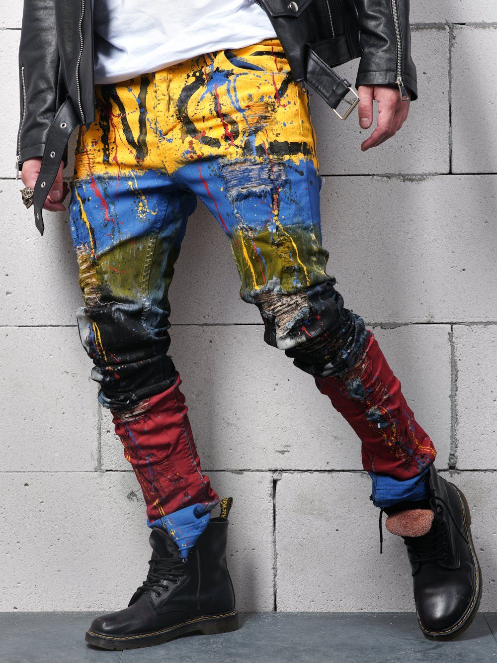 A man wearing colorful jeans and a TOO MUCH.