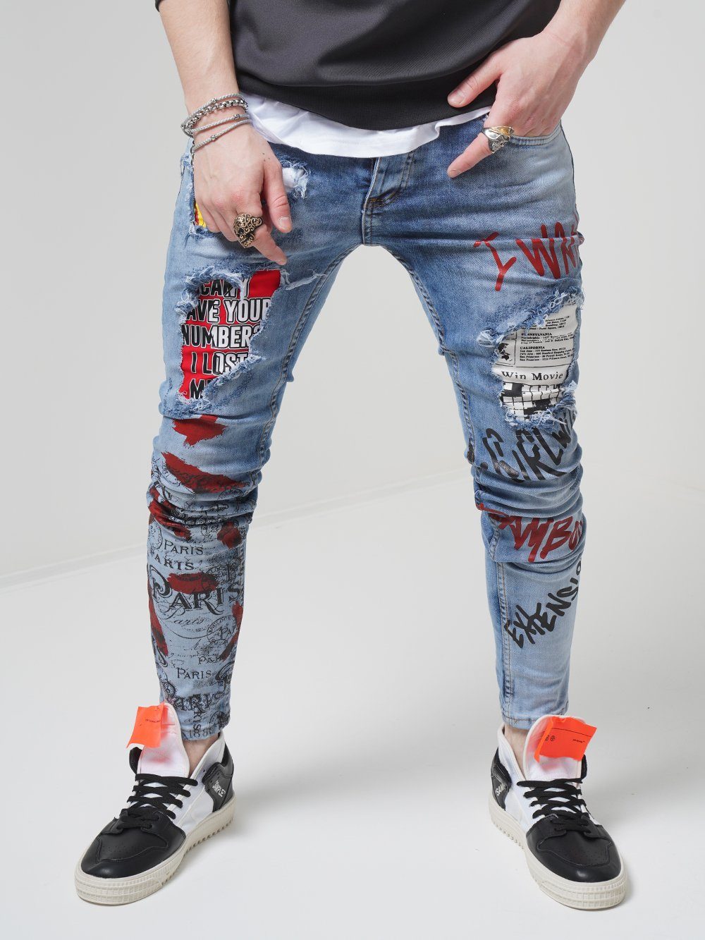 A man wearing a pair of BANKSY jeans with graffiti on them.