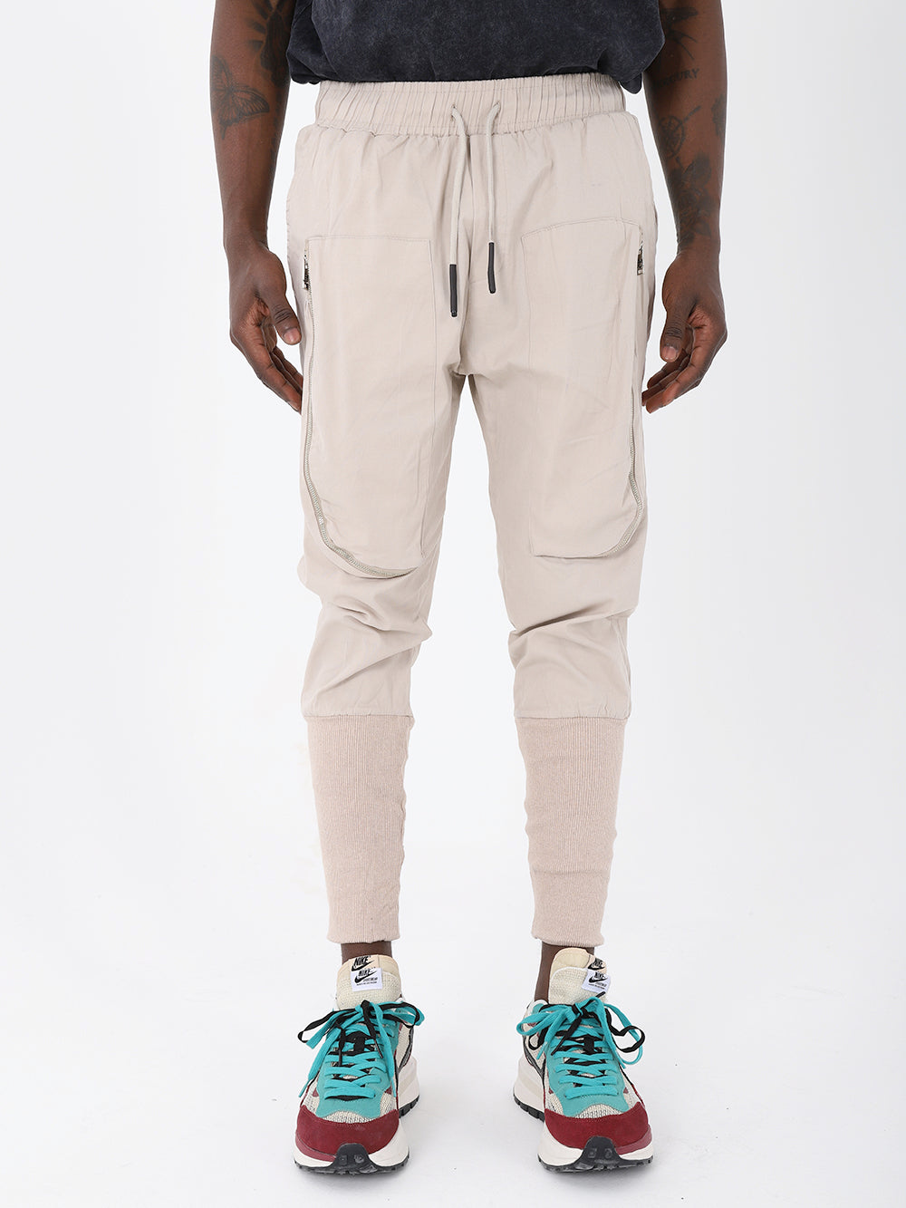 The man is wearing a fashion item - beige Altis jogger pants with an adjustable drawstring waist.