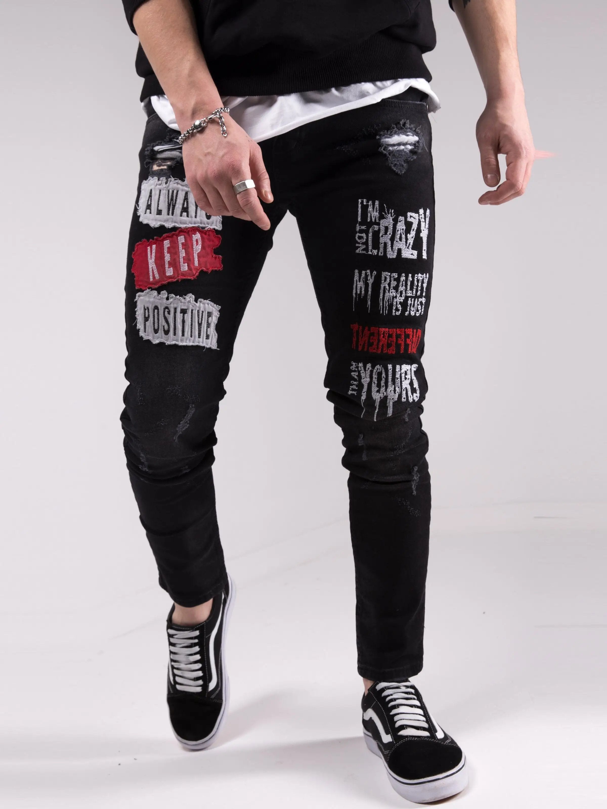 A man wearing a pair of I'M NOT CRAZY jeans with graffiti on them.