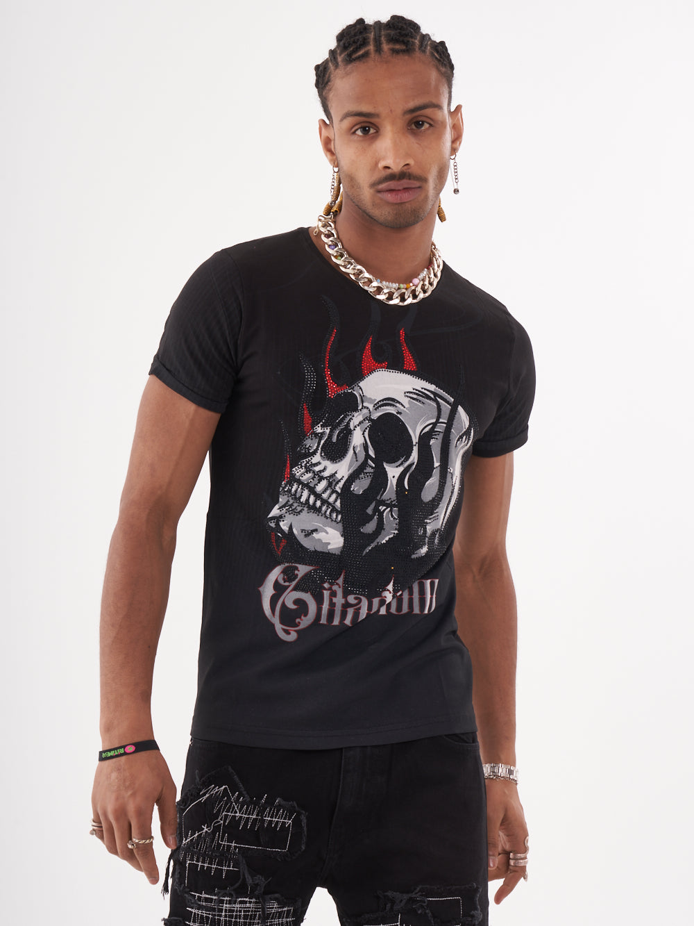 A man sporting a NIRVANA skull-print embellished T-SHIRT in BLACK, paired with patched jeans.