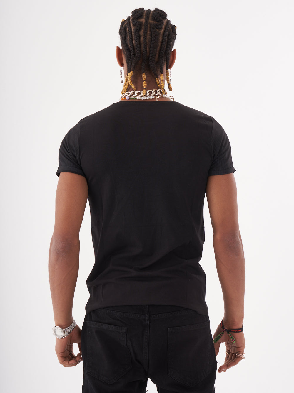 The back of a man wearing the NIRVANA skull-print embellished T-SHIRT in BLACK and relaxed fit black jeans.