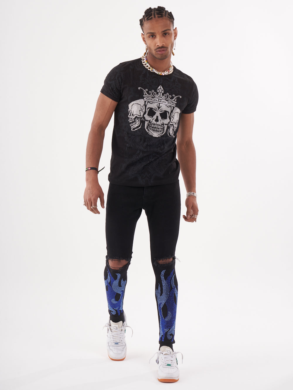 A man wearing a TRINITY T-SHIRT in black with skeleton print and slim fit blue leggings.