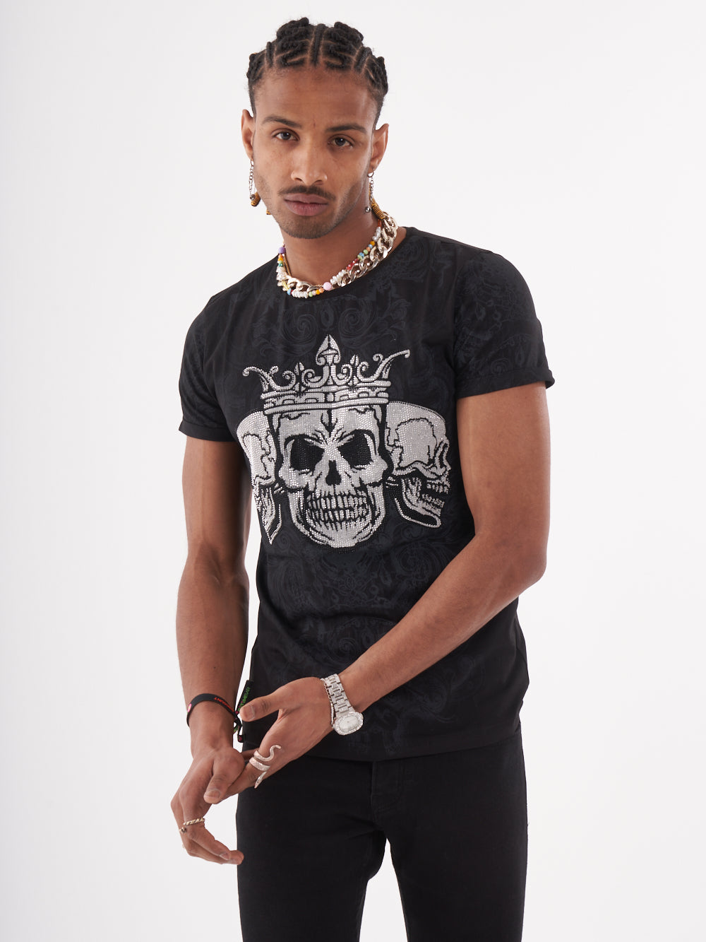 A man wearing the TRINITY T-SHIRT | BLACK with a skeleton print of a skull and crown on it.