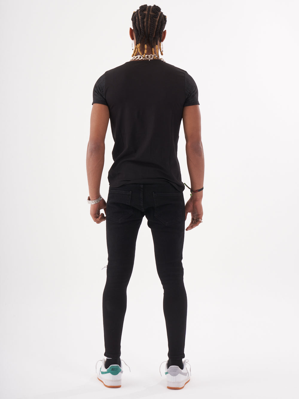 The back view of a man wearing a TRINITY T-SHIRT | BLACK and black jeans.