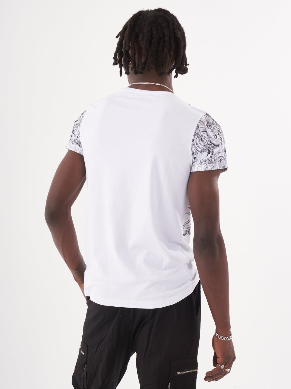 A man with an edgy style wearing a gothic-inspired TRINITY T-SHIRT | WHITE and black shorts.