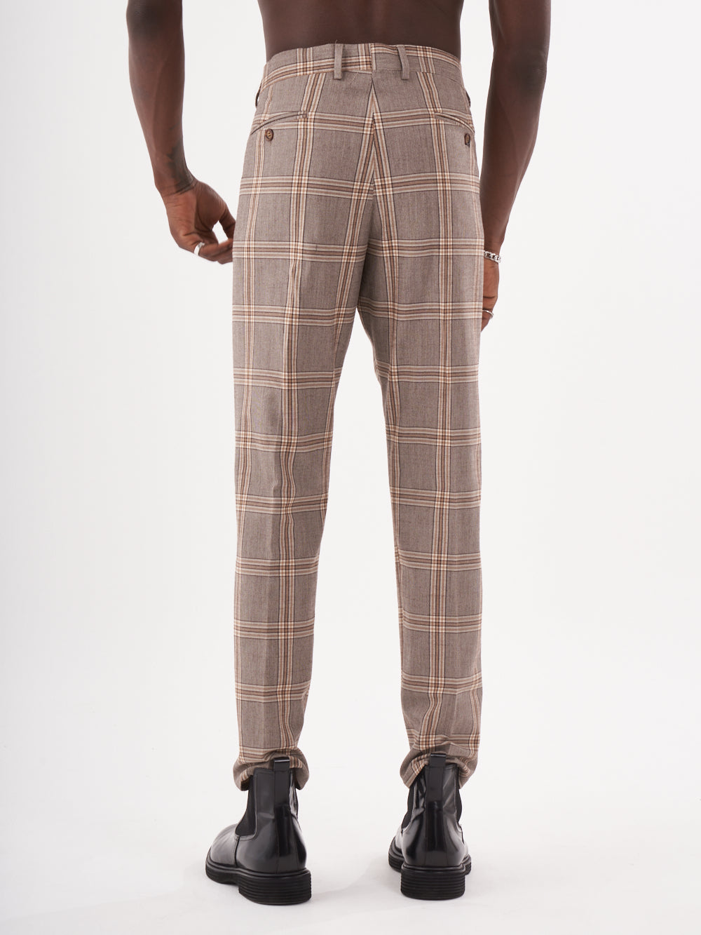 The back view of a man wearing ROOK PANTS in brown checkered trousers.