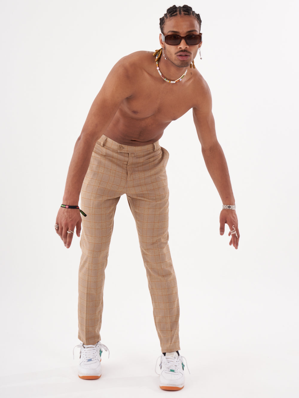 A man in a tan shirt and BAROT PANTS is posing in front of a white background.