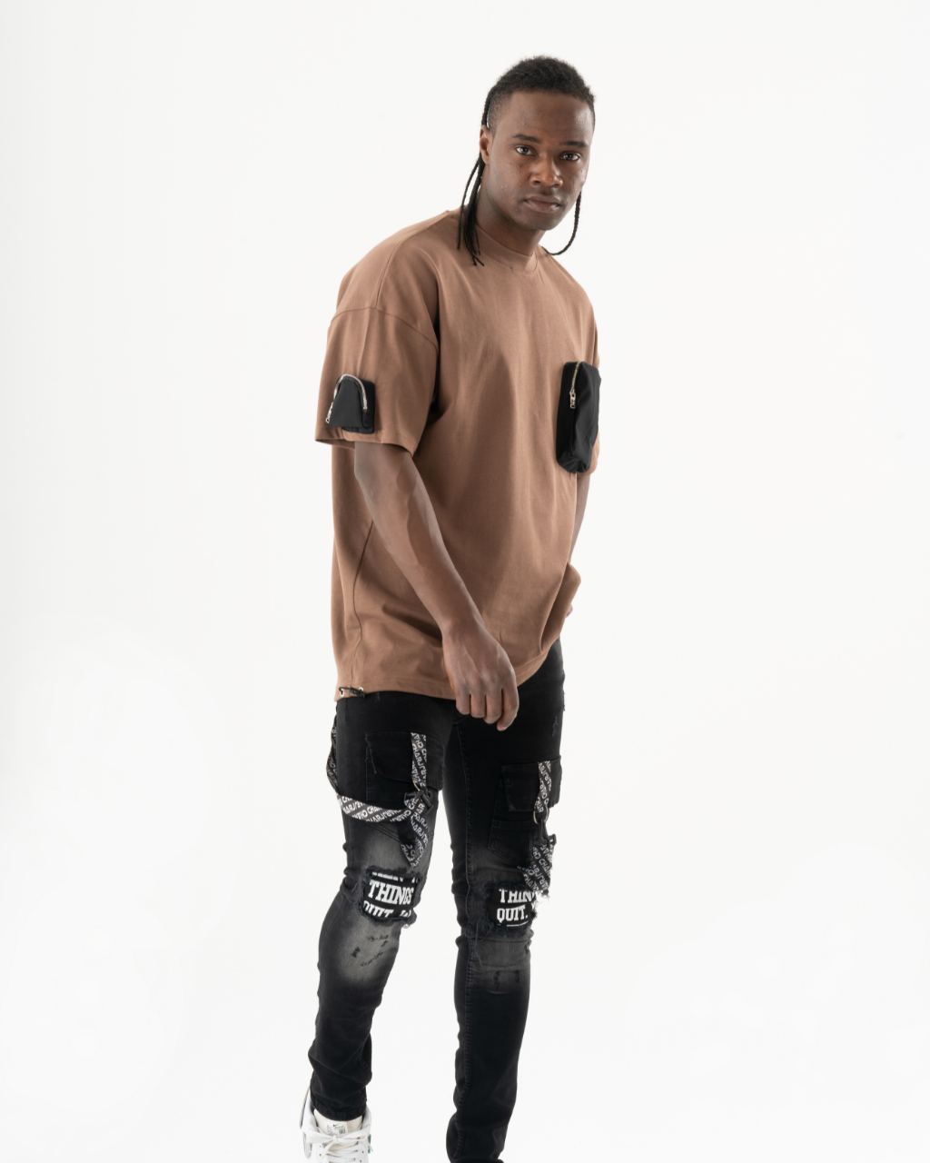 A man wearing a brown FATE t-shirt and ripped jeans.
