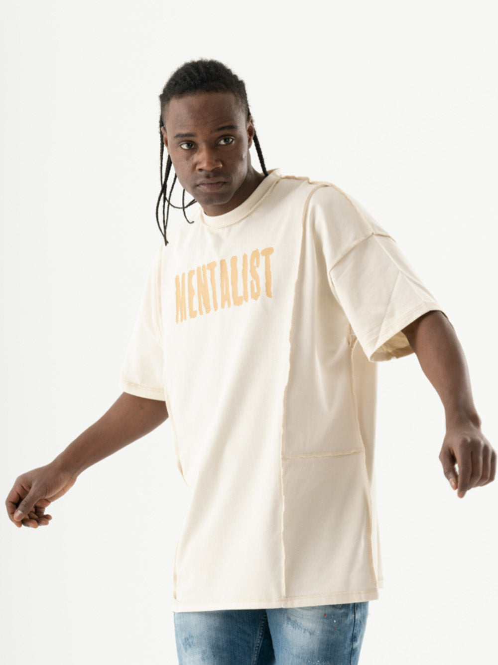 A man wearing a MENTALIST T-SHIRT | BEIGE with the word mentast on it.