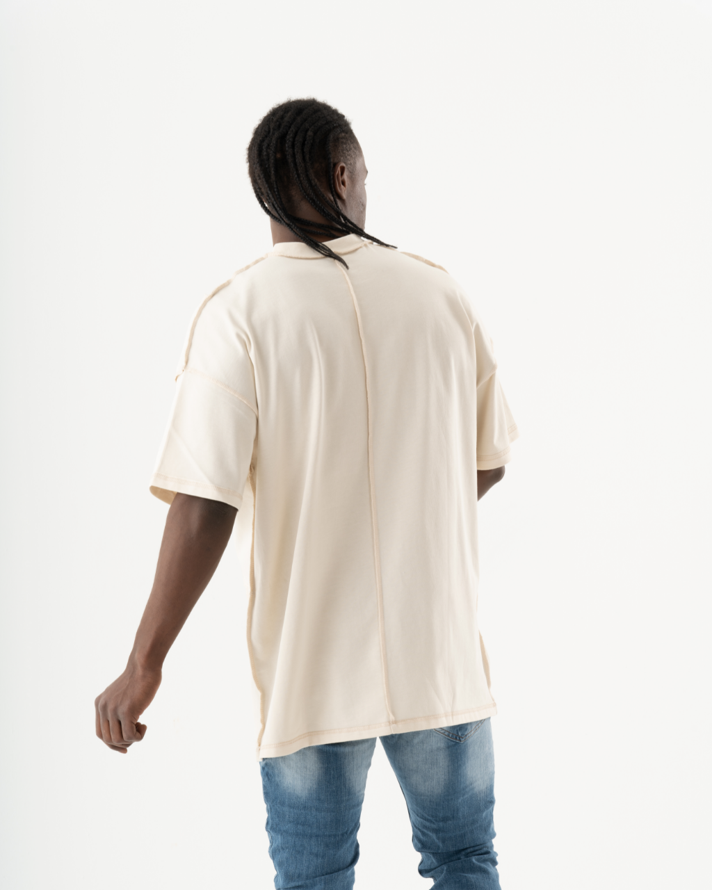 A man in jeans and the MENTALIST T-SHIRT | BEIGE is walking backwards.