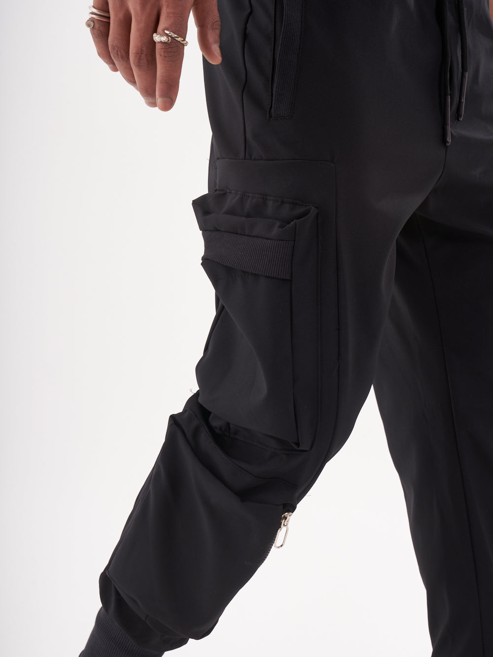 A man wearing OUTLIER JOGGERS | BLACK cargo pants with pockets.