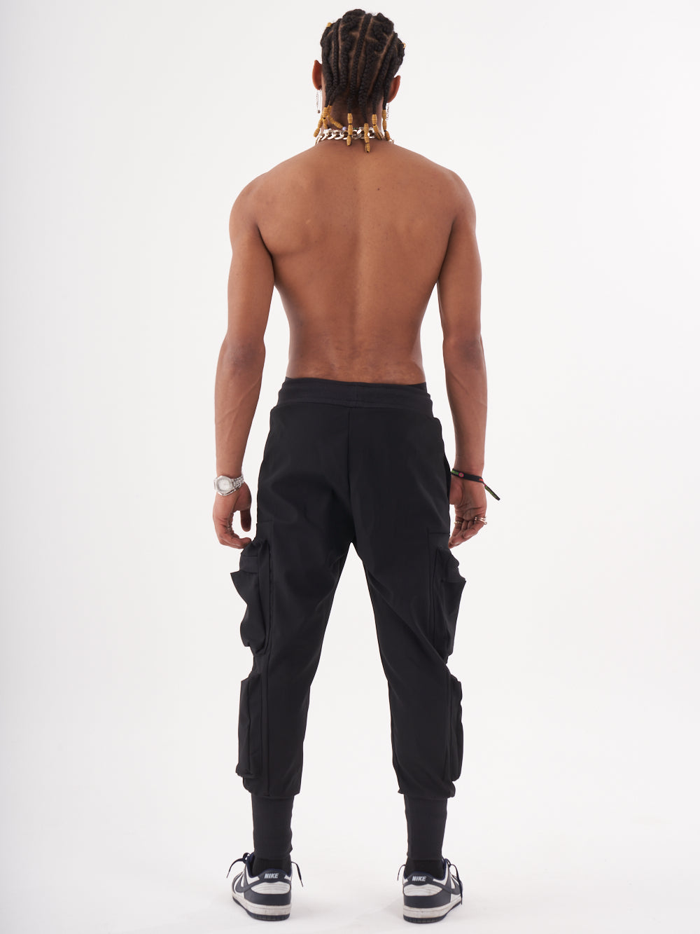The back view of a man wearing OUTLIER JOGGERS | BLACK cargo pants.