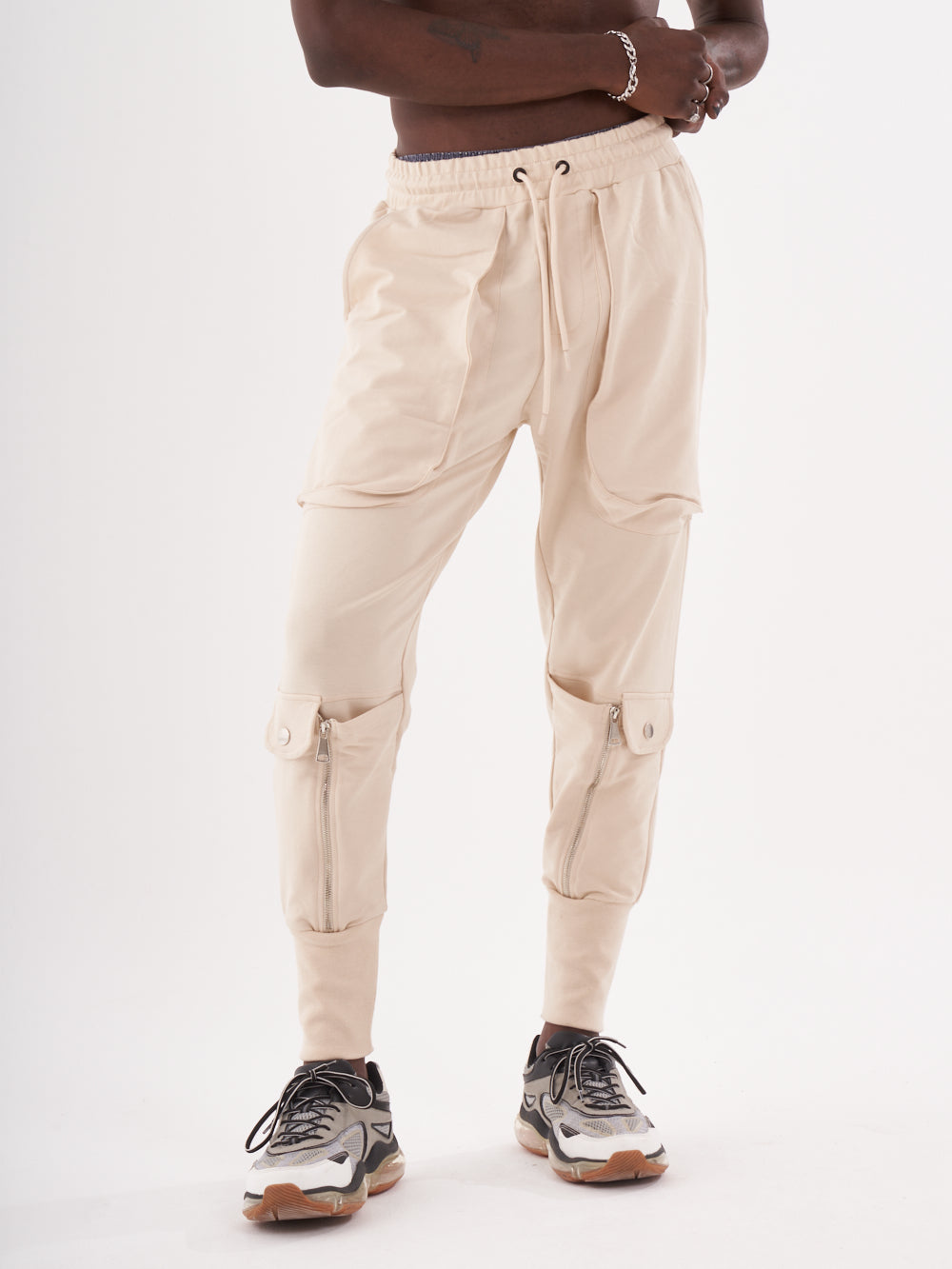A man wearing GUERRILLA | BEIGE jogger pants and a white t-shirt.