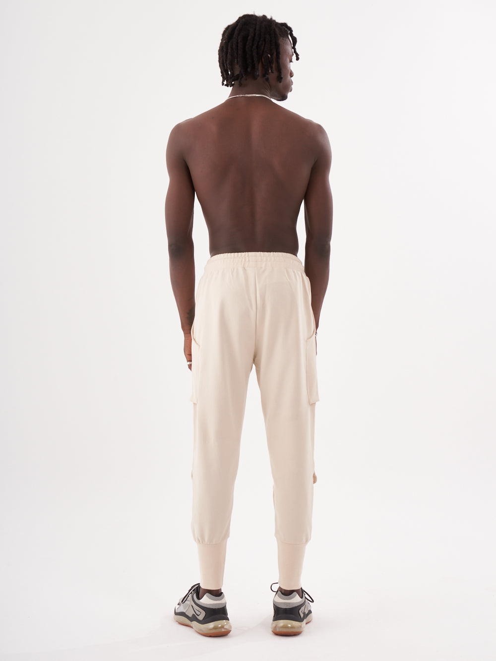 The back view of a man wearing GUERRILLA | BEIGE cargo pants.