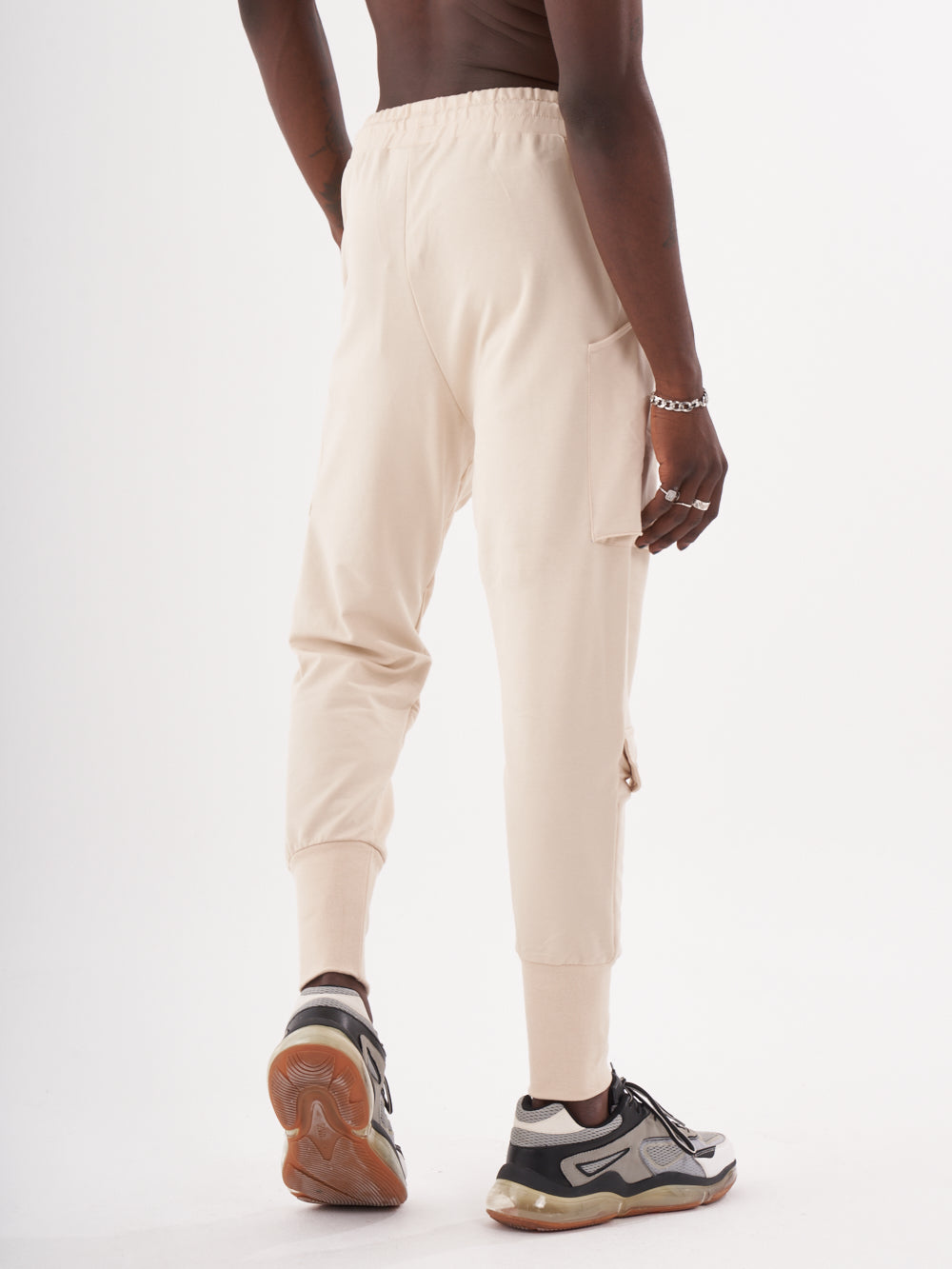 The back view of a man in GUERRILLA | BEIGE sweatpants.