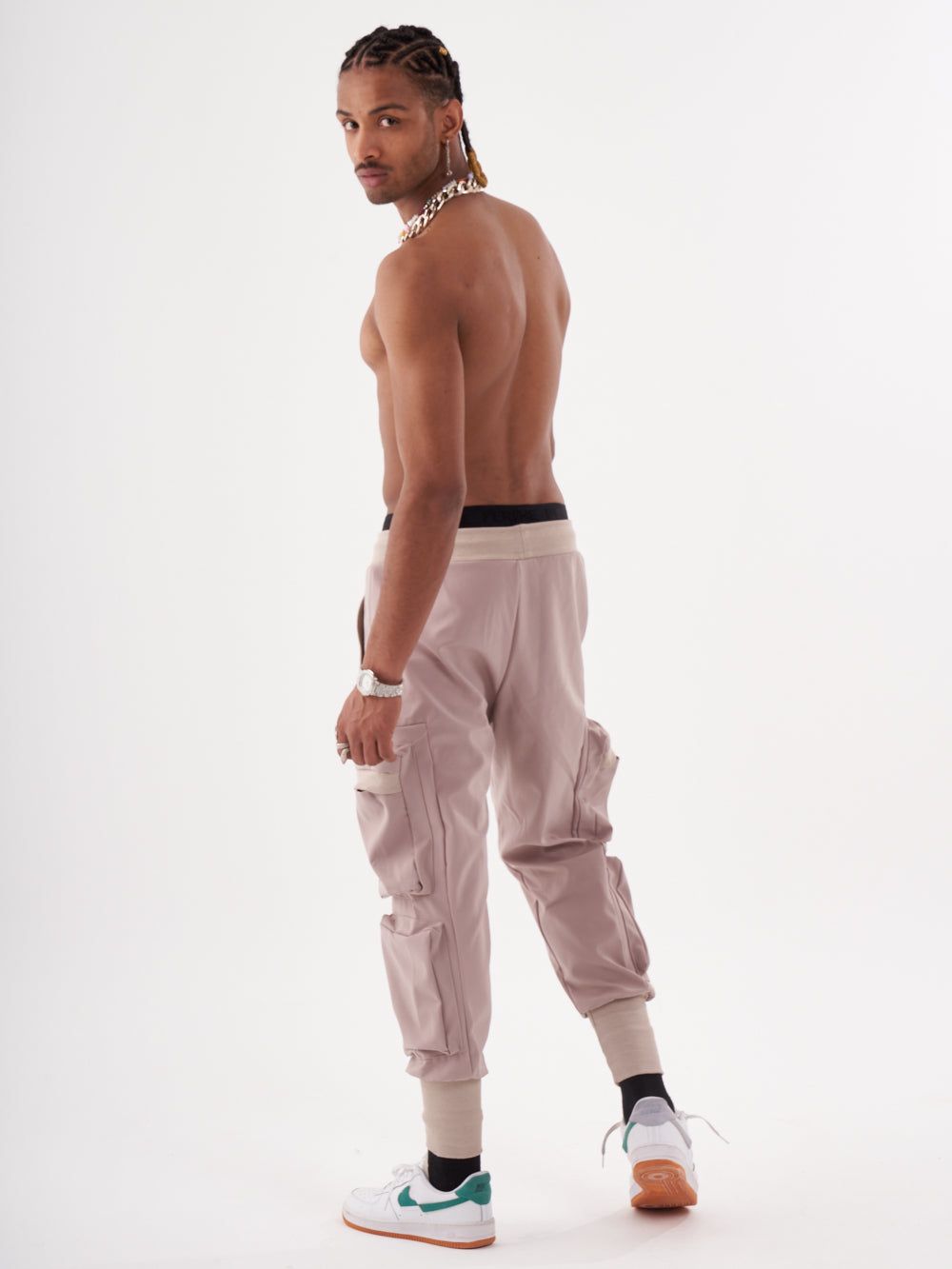 A man in OUTLIER | MAUVE jogging pant is standing in front of a white background.