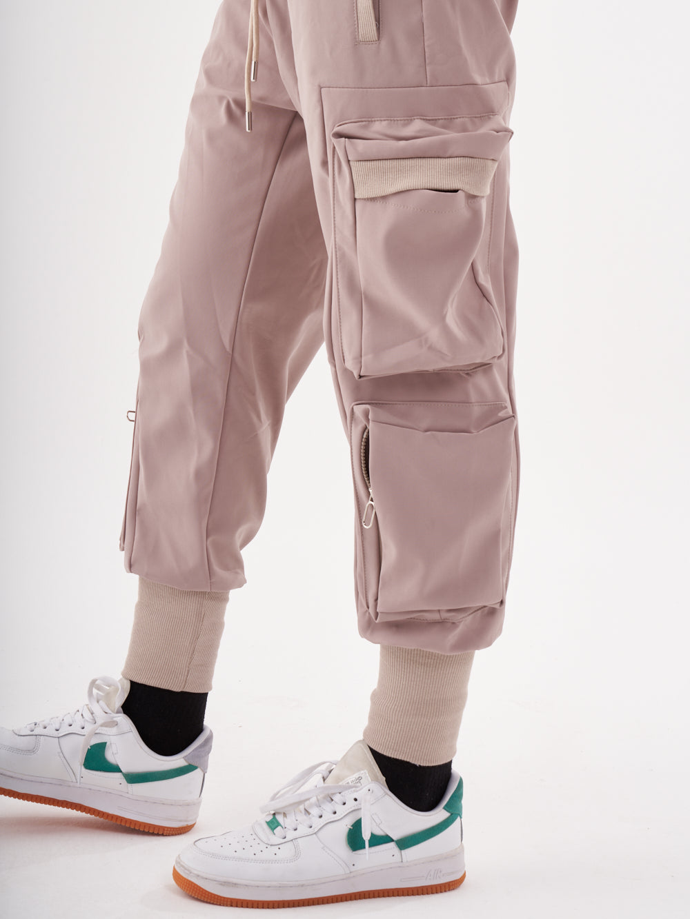 A man wearing OUTLIER | MAUVE cargo pants and white sneakers.