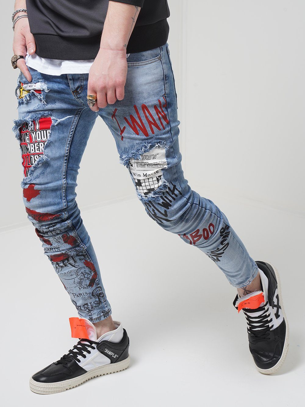 A man wearing a pair of BANKSY jeans with graffiti on them.