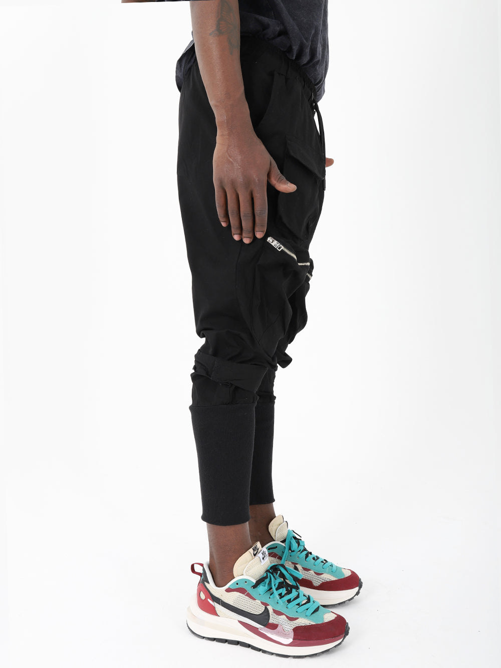 A man wearing MEREEN jogger pants and sneakers.