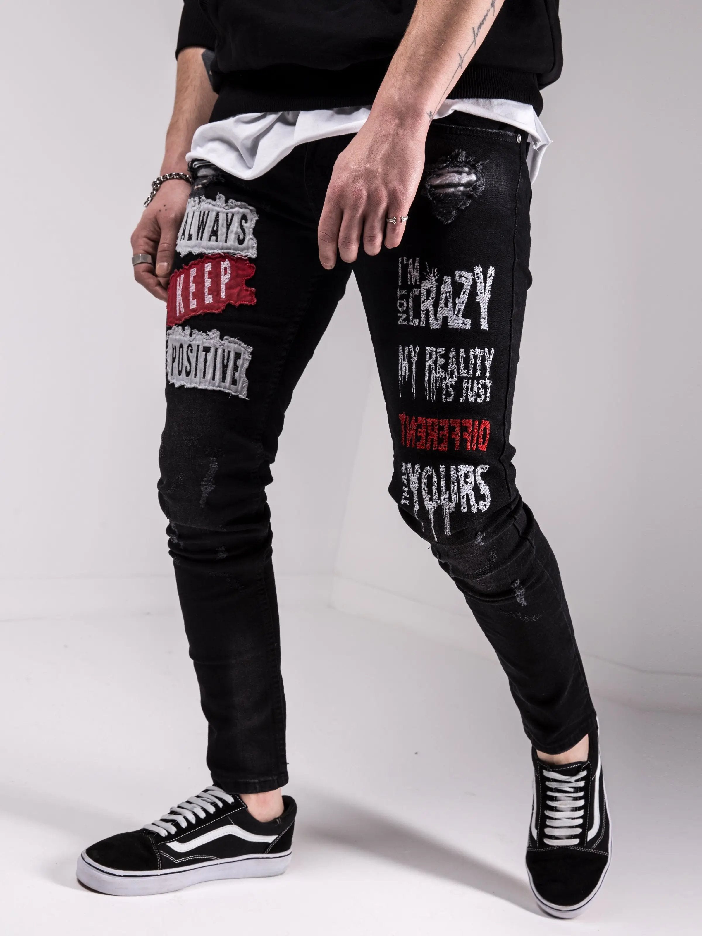 A man wearing a pair of I'M NOT CRAZY jeans with graffiti on them.
