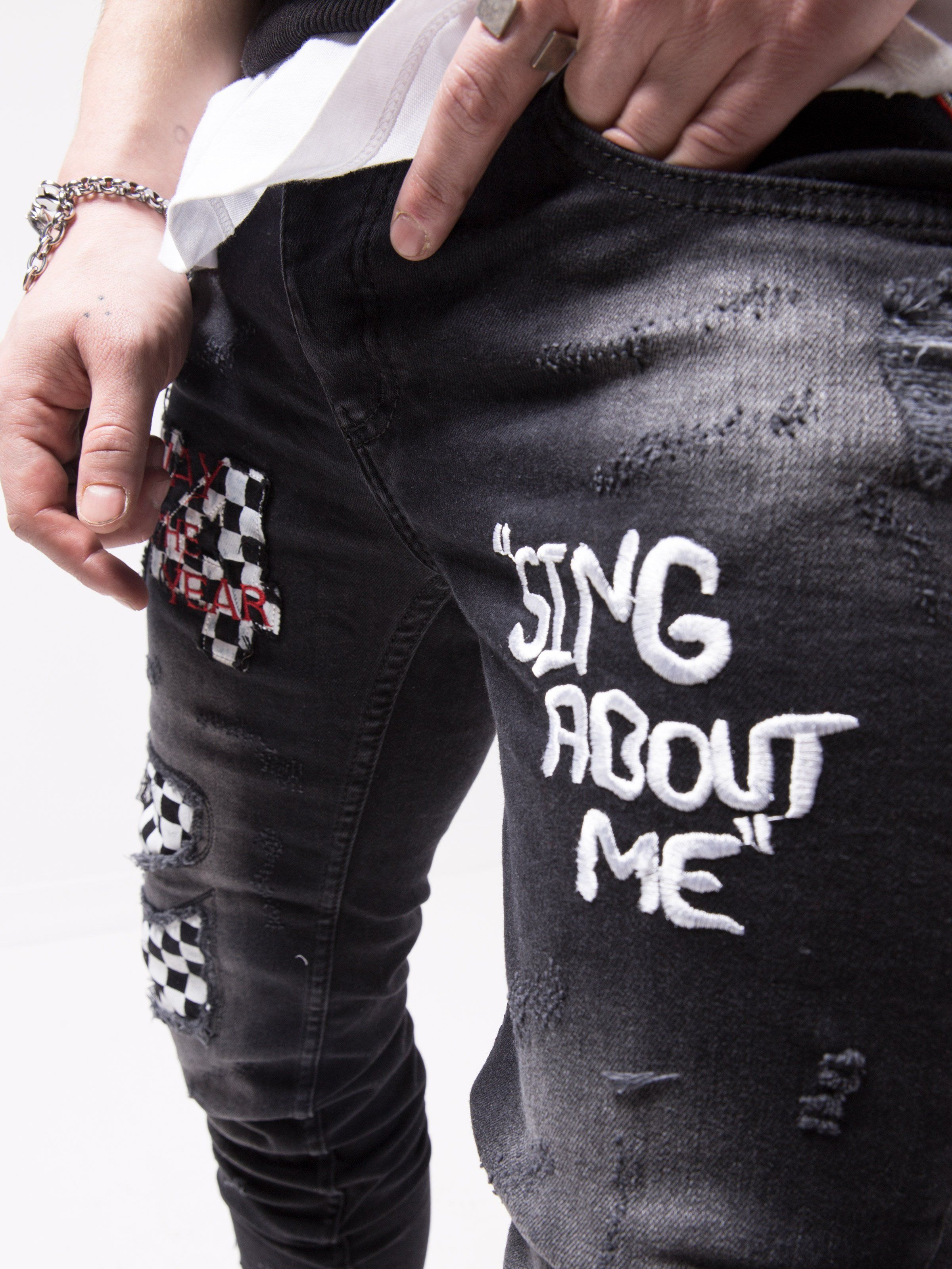 A man wearing a pair of FORMULA TROPHY jeans that say sing about me.