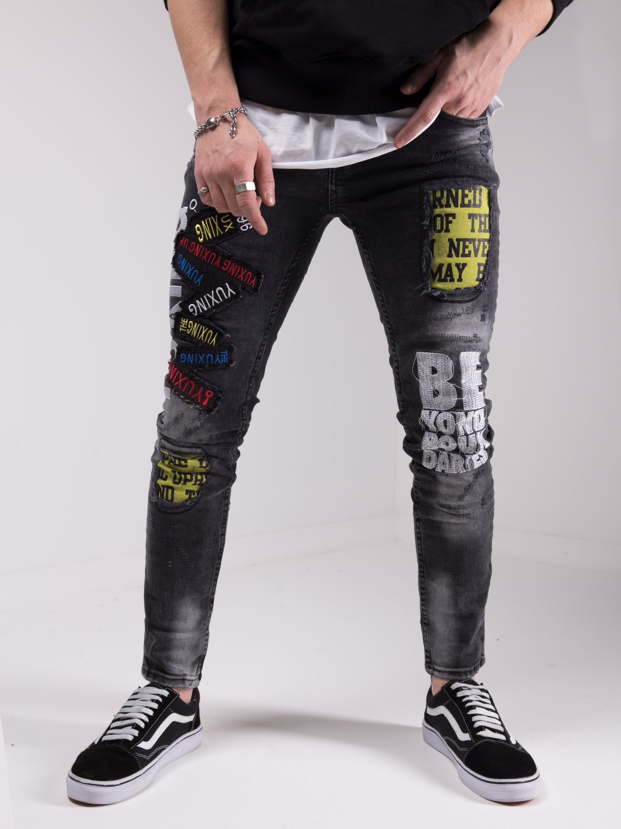 A man wearing a pair of SAVAGE SECRET jeans with patches on them.